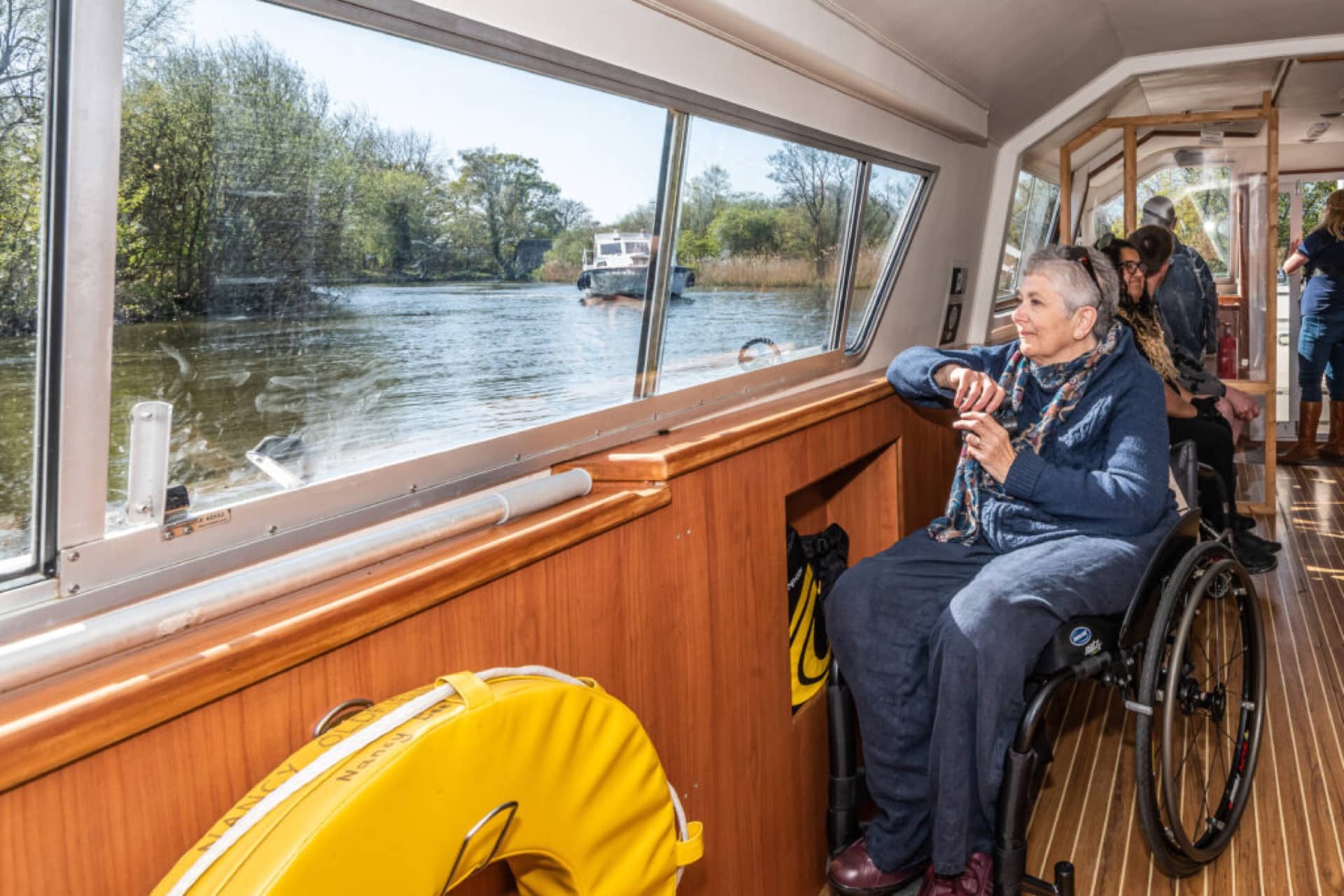 A woman looks out the window of a motorboat heading down the Norfolk Broads