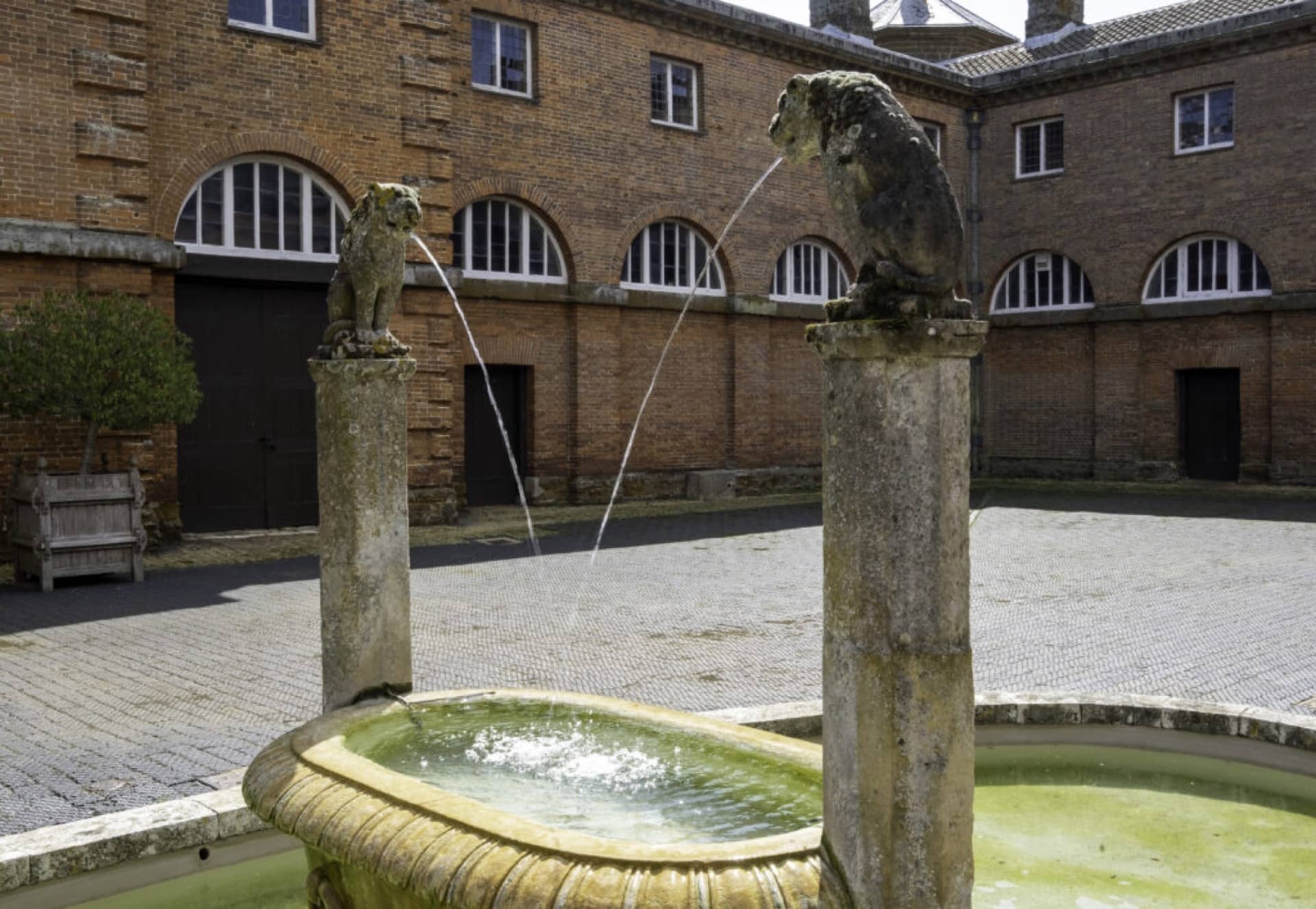 A stone water feature with sculpted lions in the stable courtyard of Houghton Hall, Kings Lynn Norfolk