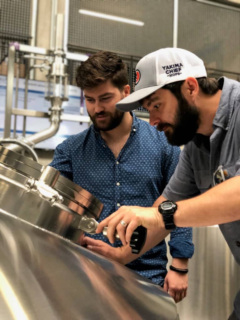 Two men look into a brewery barrel in Norfolk.