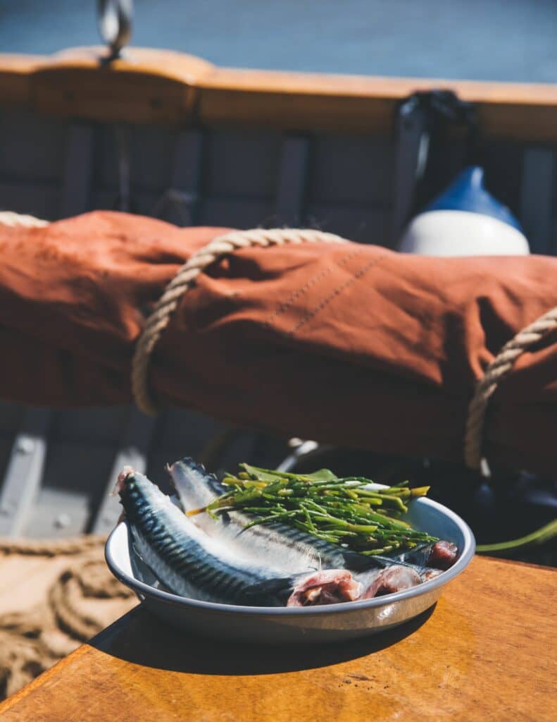 Two fish and asparagus in a mixing bowl on a boat