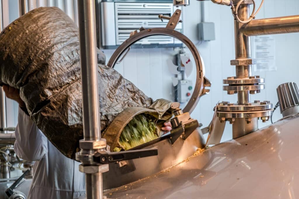 A man pouring in yeast into a vat to make beers.