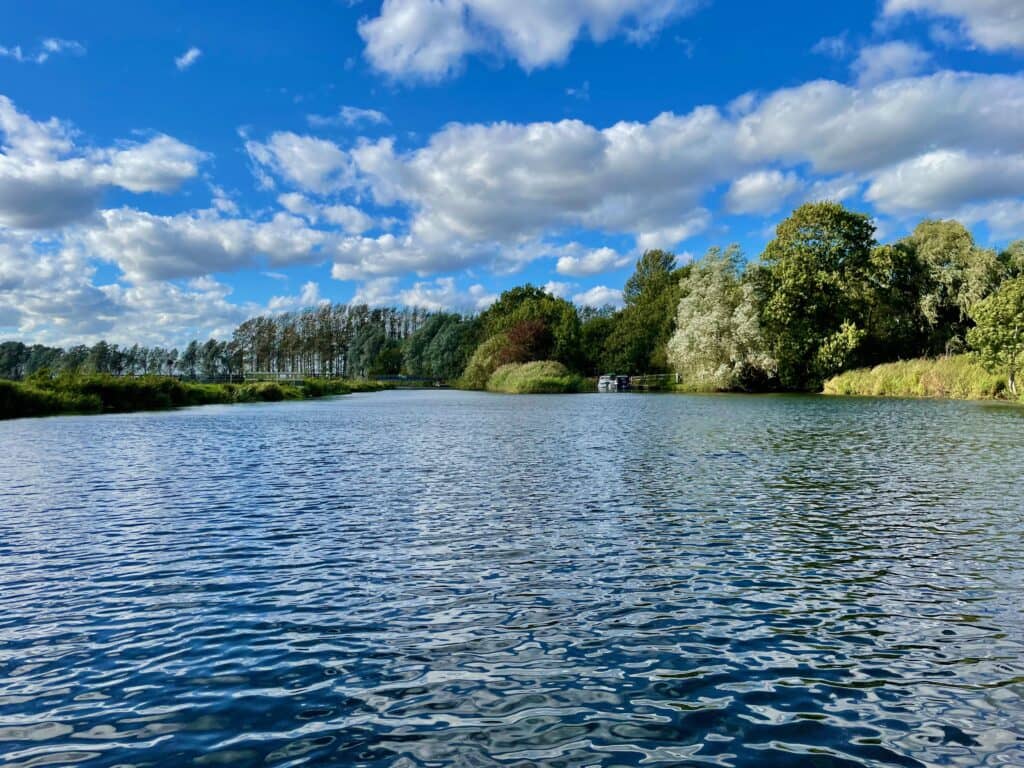 Blue sky over a rippling river with green trees on the riverbank