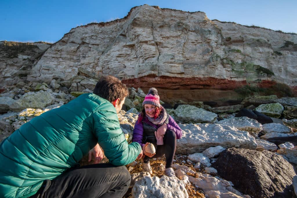 Two people look at rocks next to the Hunstanton Cliffs.