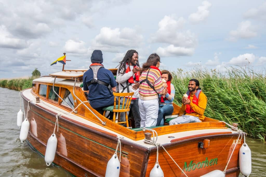 Group of people having afternoon tea on river in Moorhen Cruiser