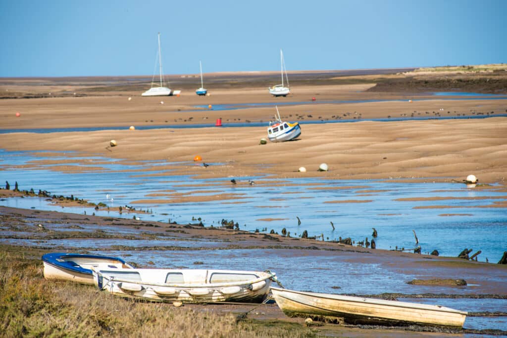 urful boats marooned on sandbanks at low tide