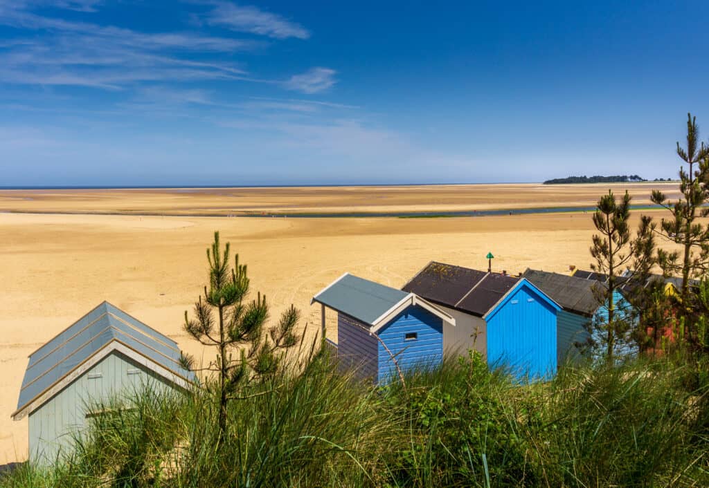 Seaside beach huts at low tide against sandy beach