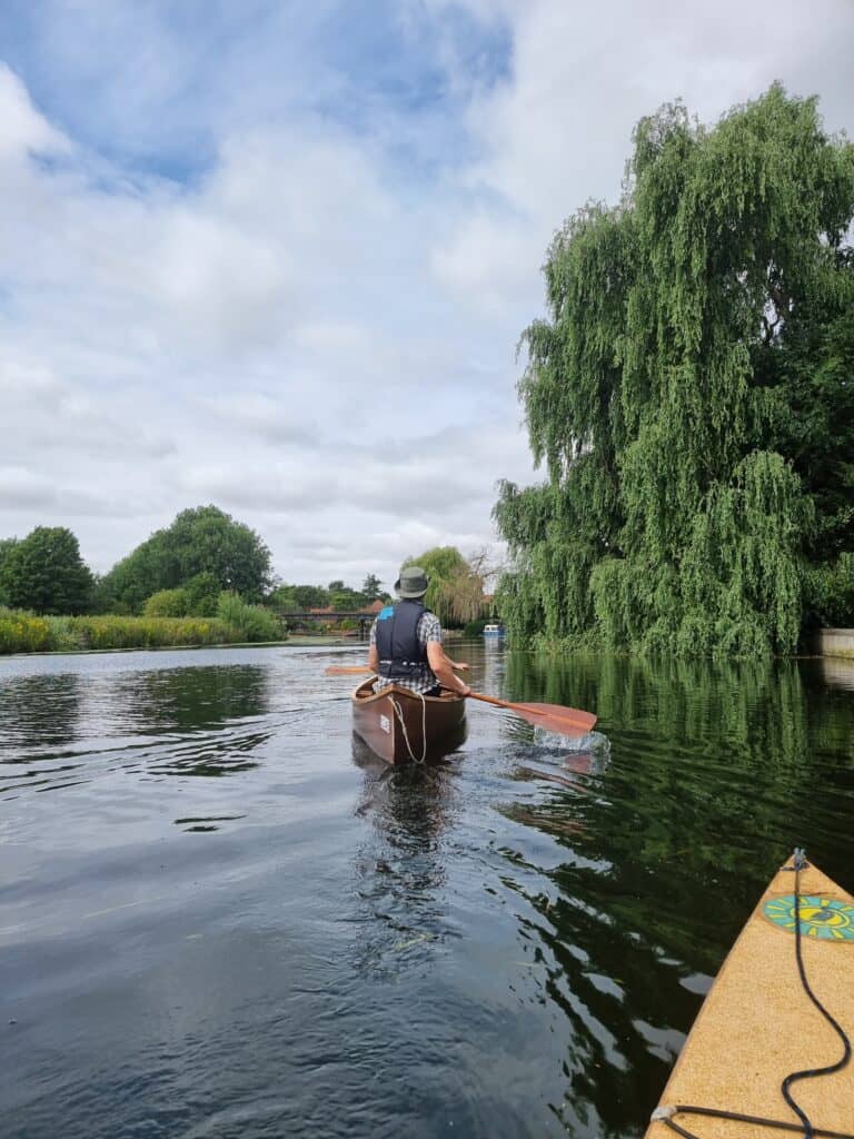 Man paddling down the River Yare in open top canoe