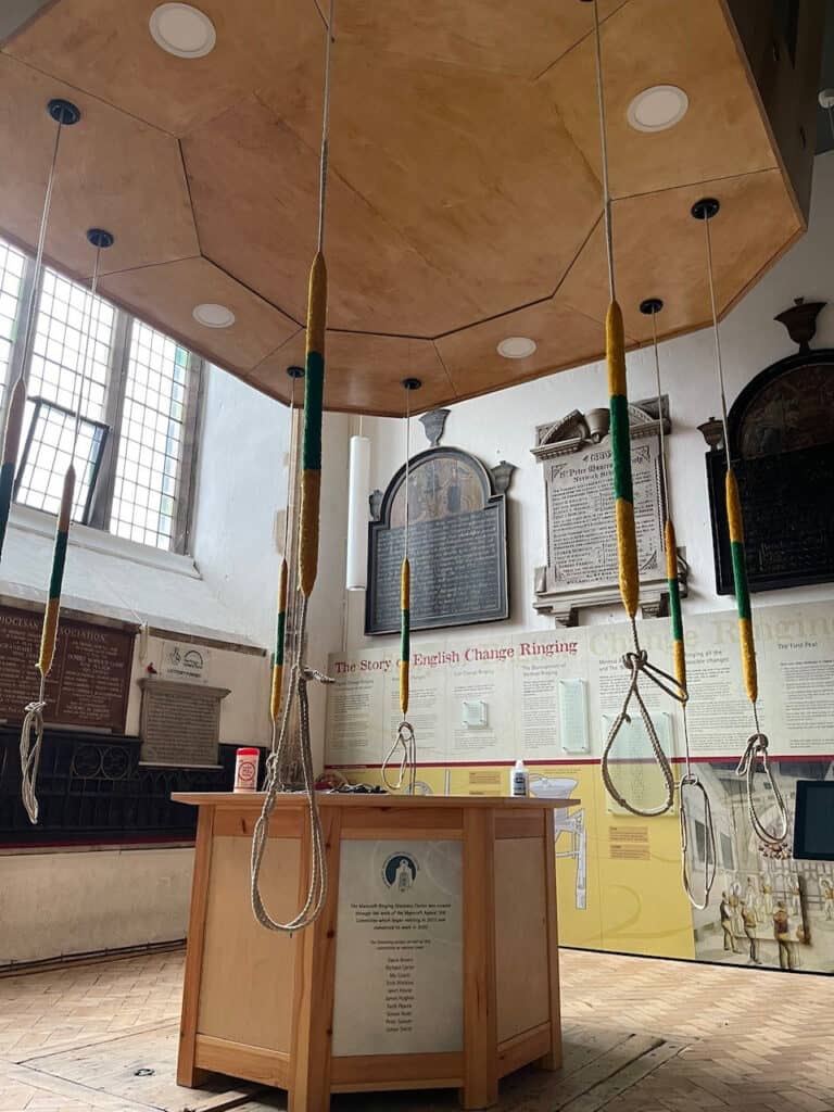 Inside a bellringing tower with a centre wooden table and a range of pulls for the bell.