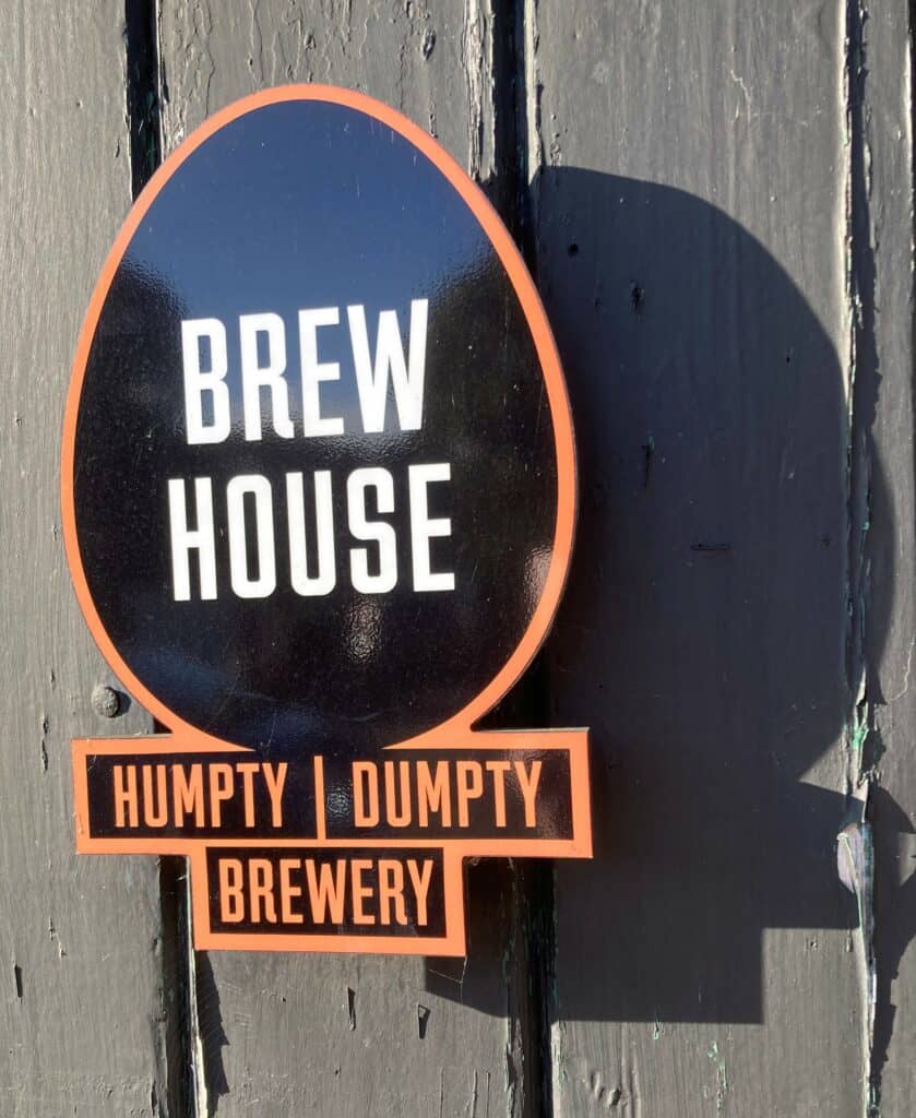 The sign for Humpty Dumpty Brewery is pictured on a wooden fence.