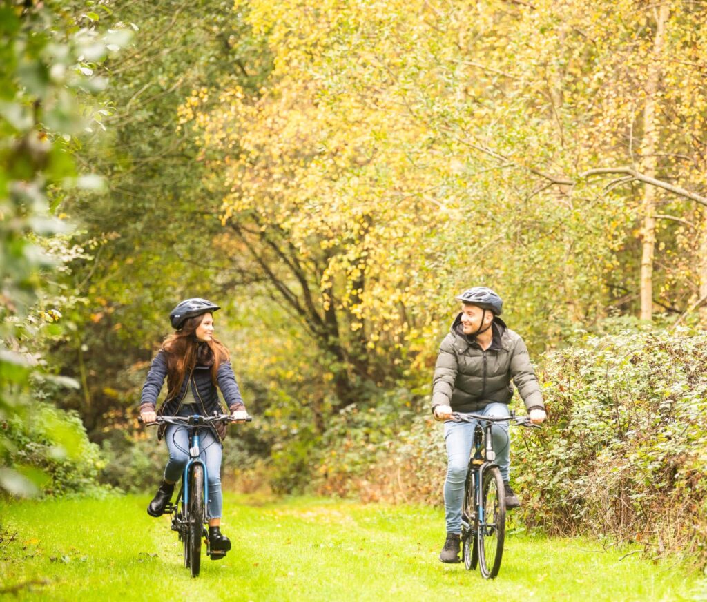 A man and woman cycle down a grassy track