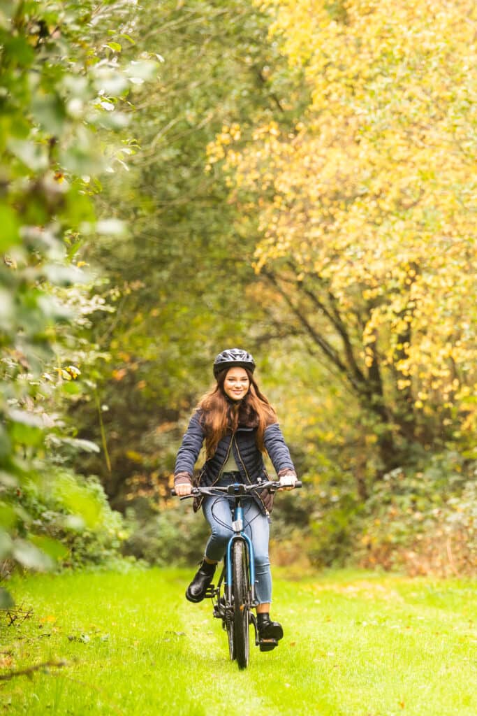 A woman cycles down a grassy track