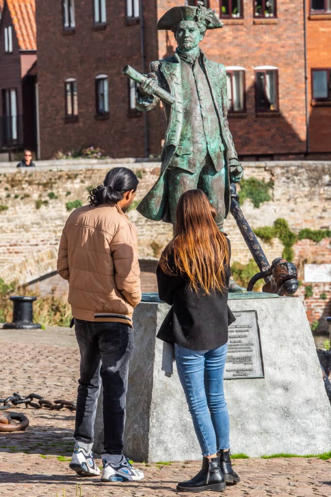 A man and woman read the inscription on the George Vancouver statue in Kings Lynn.