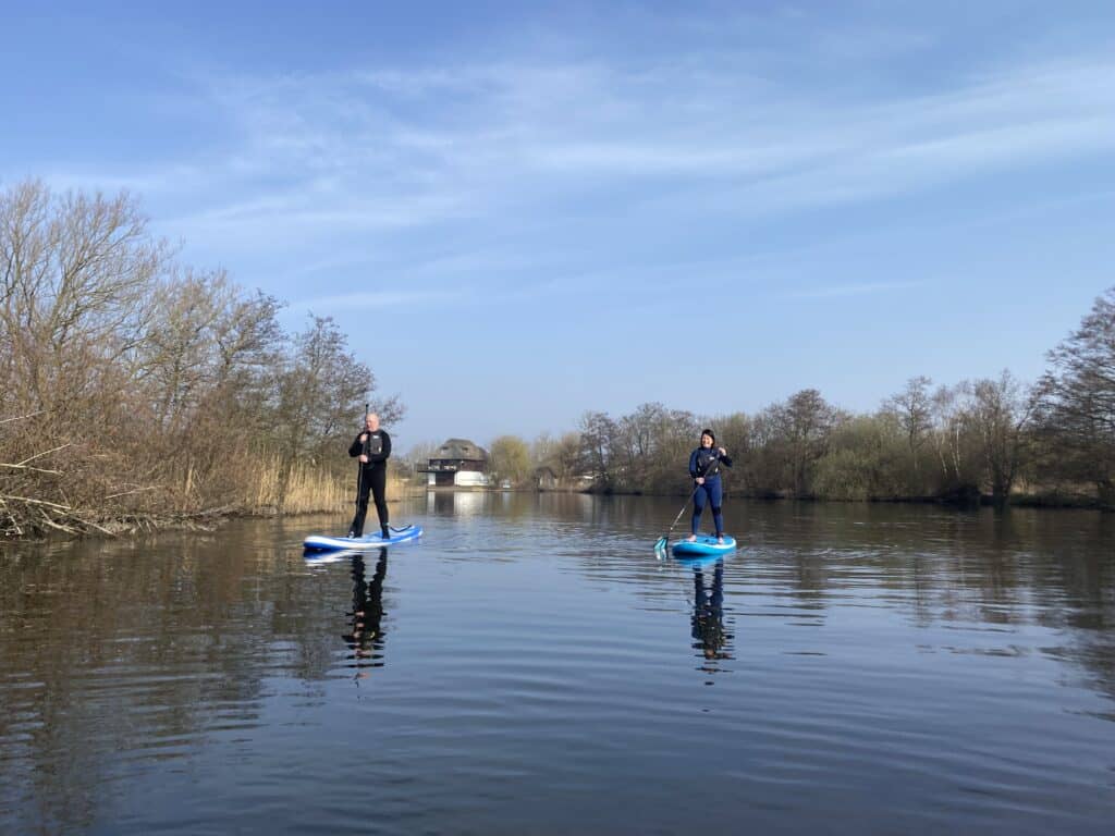 A group of people paddleboarding down the Norfolk Broads.