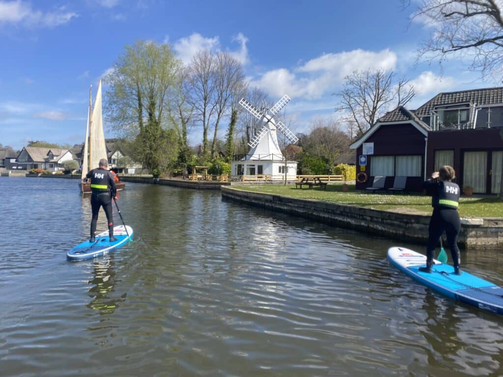 A group of people paddleboarding down the Norfolk Broads.