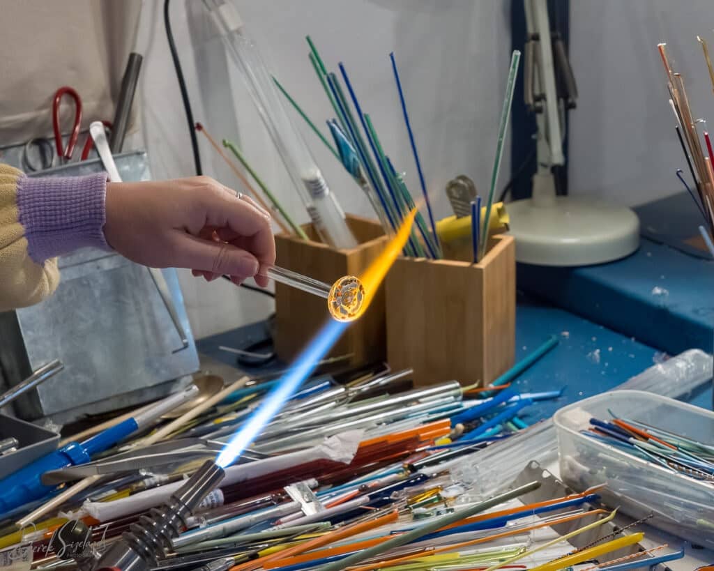 A woman holds a piece of glass over a controlled flame in her studio in Norfolk.