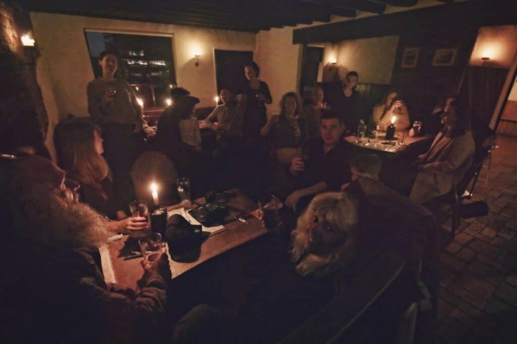 A dark room lit by candles with people sitting at tables