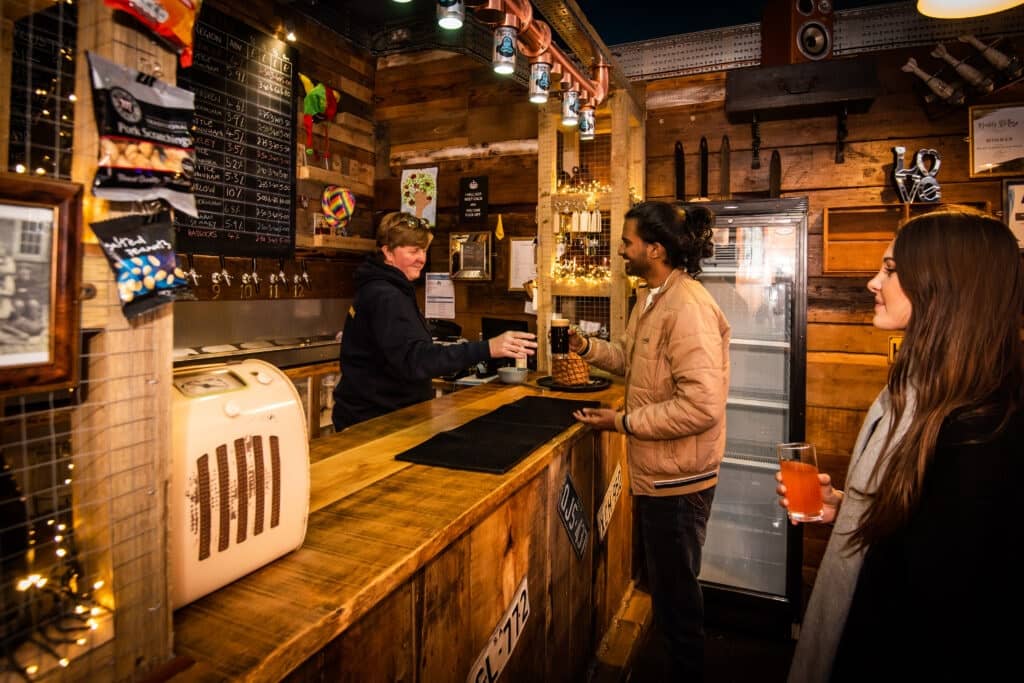 A man and a woman order drinks at a bar inside Nip and Growlers Ale House in Norfolk.