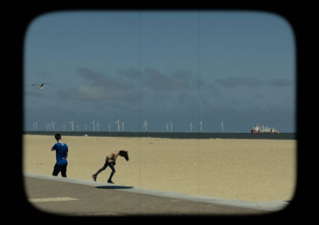 A postcard of two people on a snady beach.