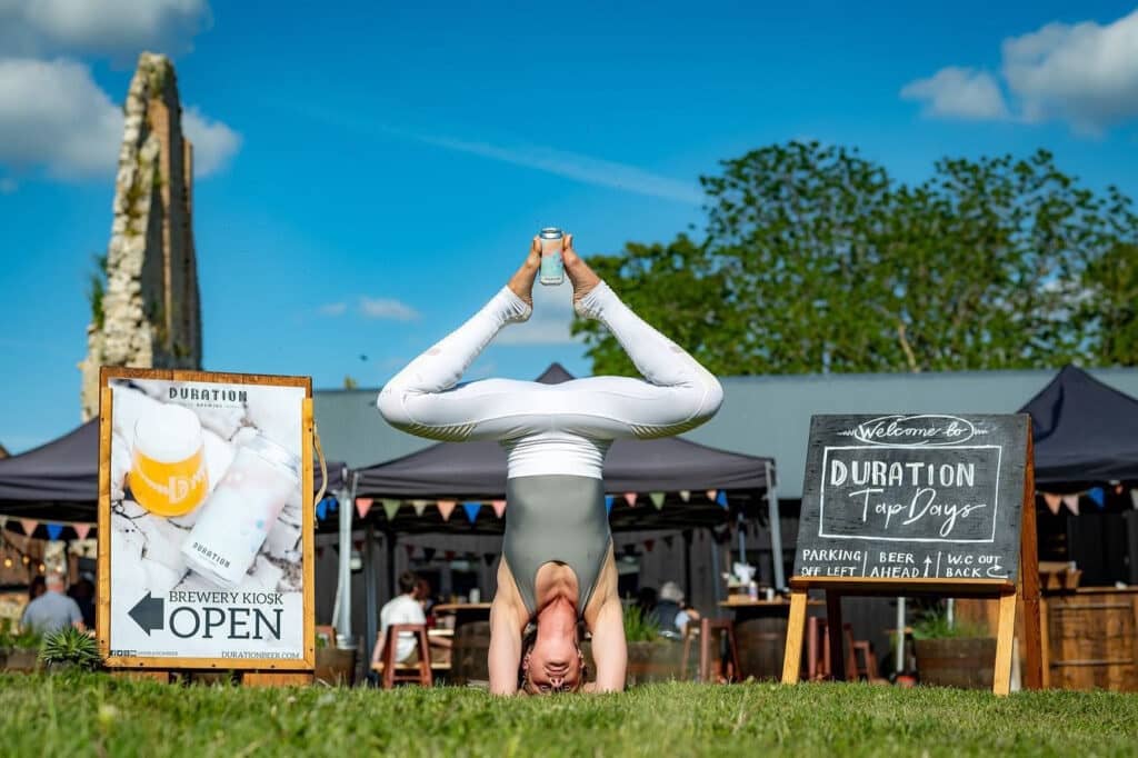 A woman doing yoga upside down with a can of beer between feet