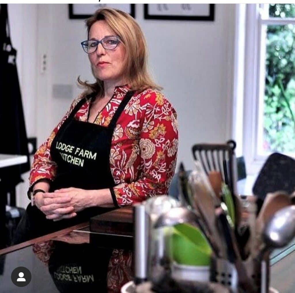 A woman poses in a kitchen with an apron on.