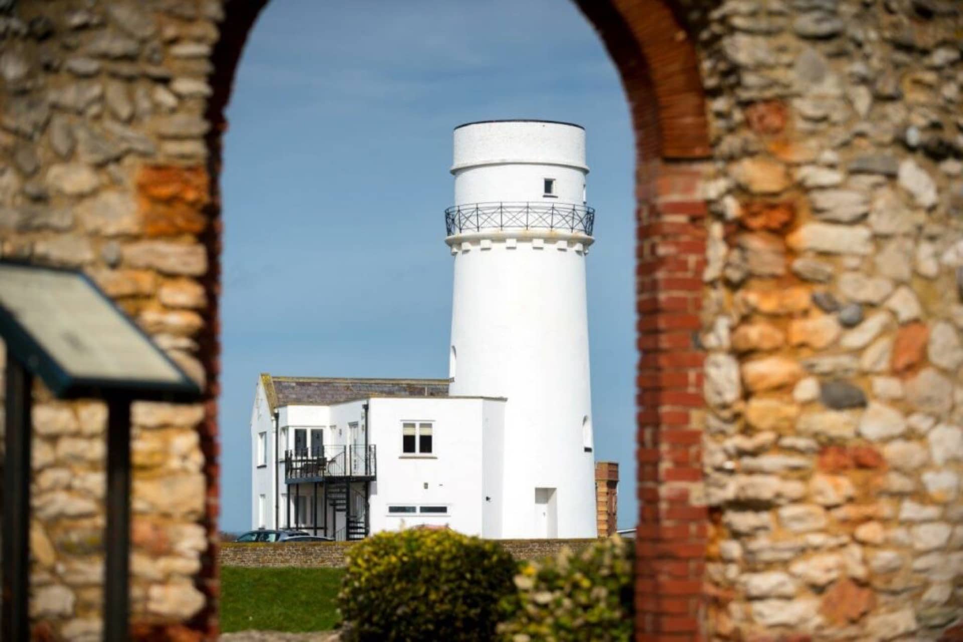 A lighthouse shown through an old brick door way