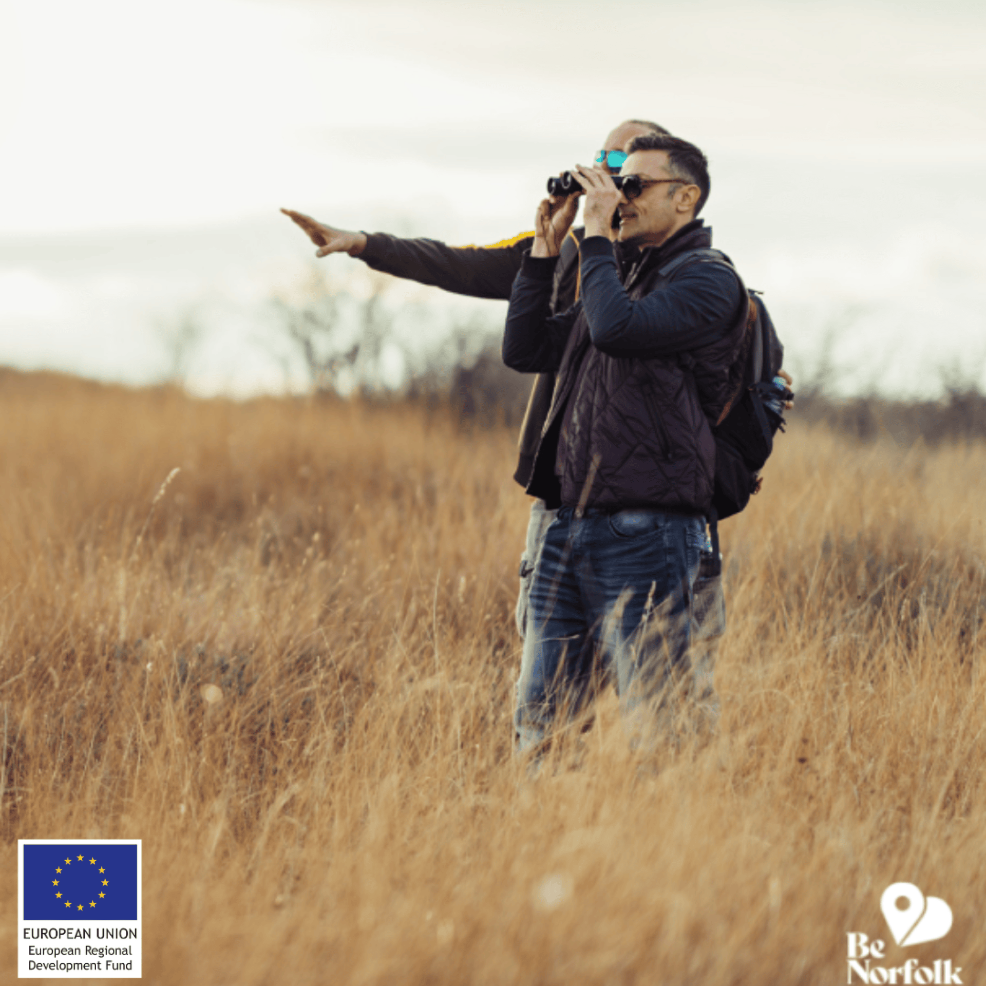 Two men using binoculars in a field