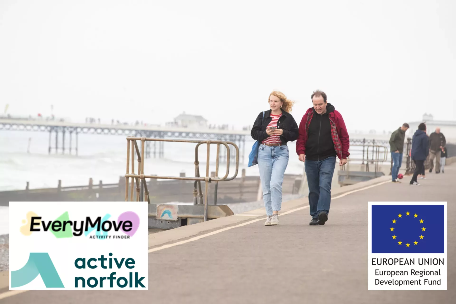 A man and a woman walking along a road next to the sea