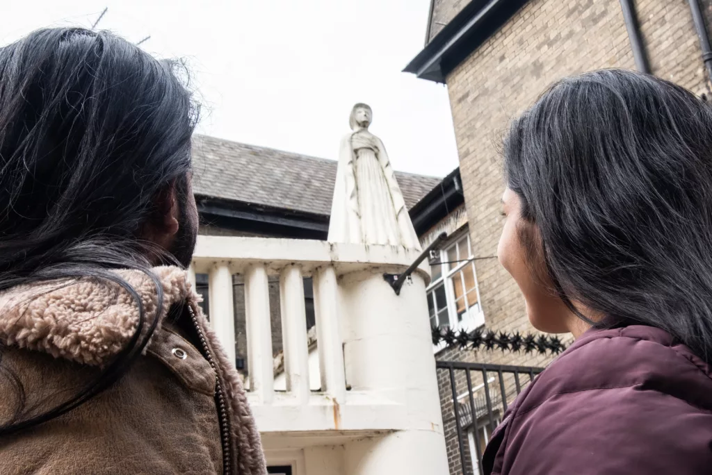 Two people looking at a statue of Amelia Opie