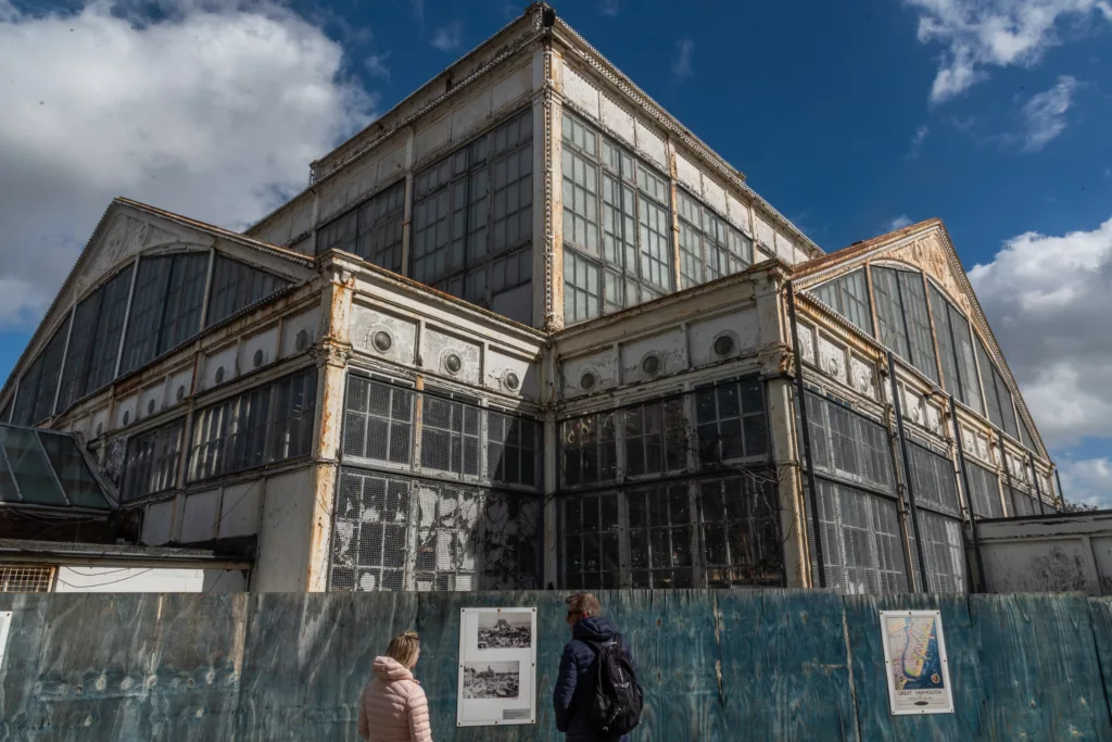 Two people standing behind safety barriers in front of the Winter Gardens, Great Yarmouth