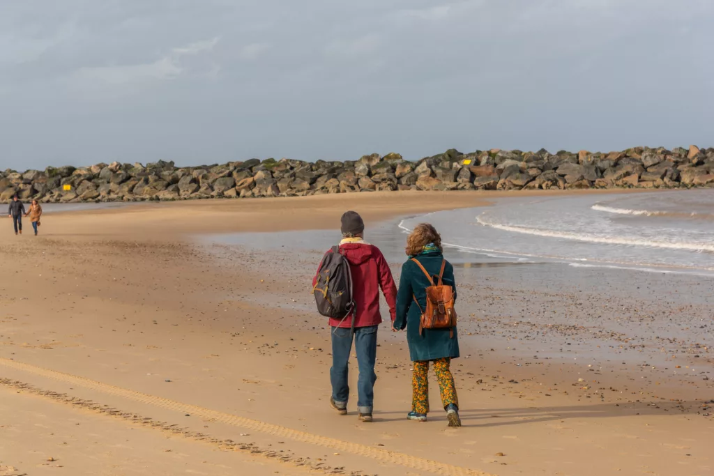 A man and a woman walking on the sandy beach at Sea Palling