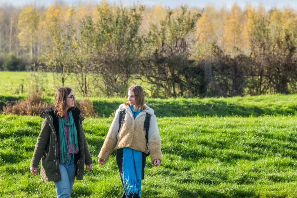 Two women chatting and walking in a field on a sunny day