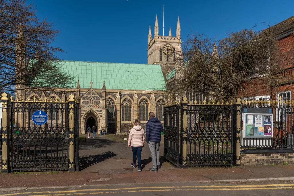 Two people walking through the gates of Great Yarmouth Minster