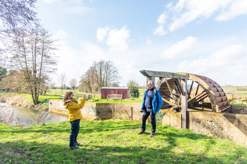 A woman takes a photo of a man at Narborough Bone Mill