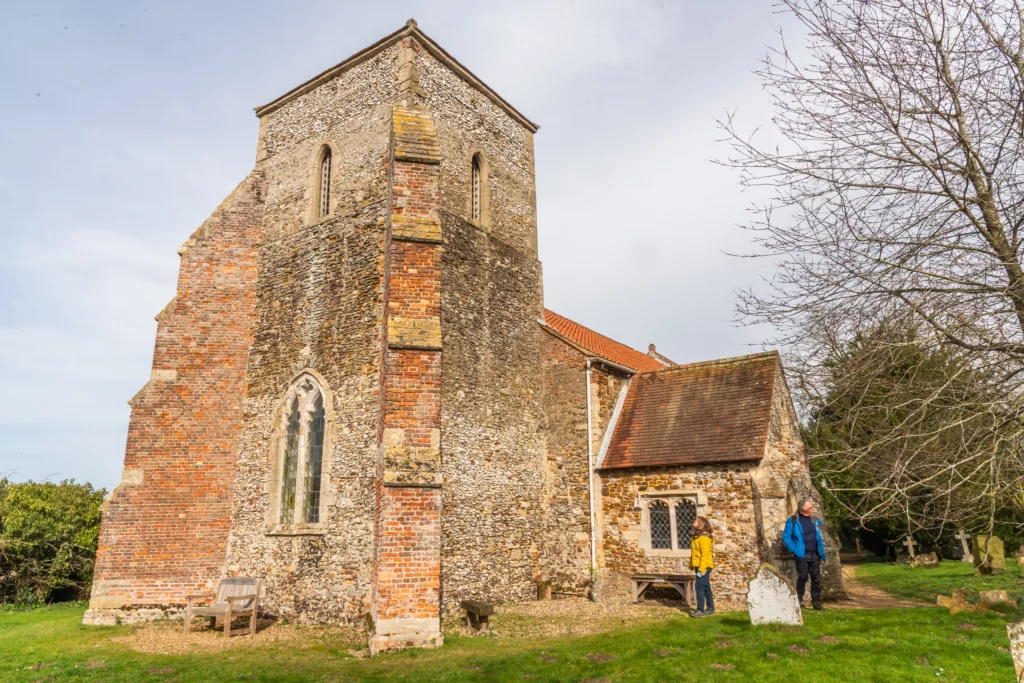 Two people standing outside All Saints Church, Ashwicken