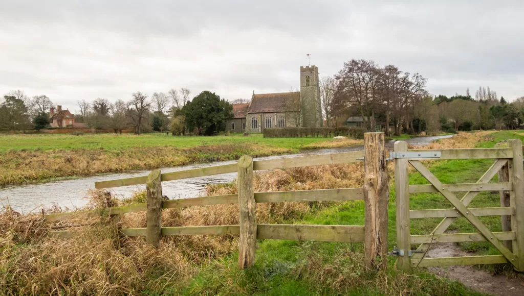 A wooden fence and gate securing entry and exit to the public footpath along the River Bure in the Norfolk village of Buxton.