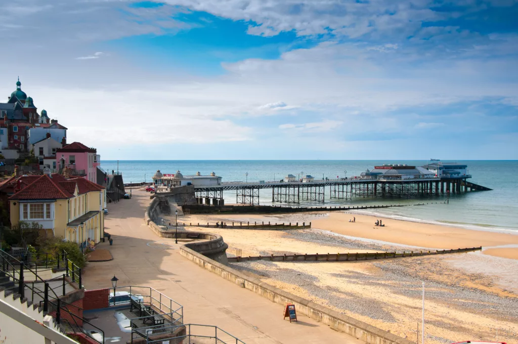 A view of the promenade, beach and pier at Cromer on a sunny day.