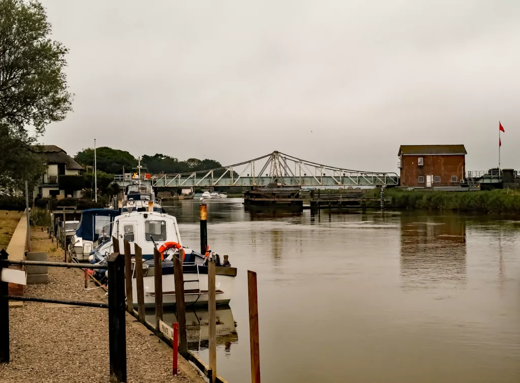 A view down the River Yare towards the metal swing bridge in the village of Reedham in the Norfolk Broads National Park.